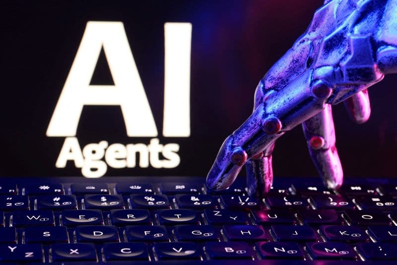 A robotic hand typing on a keyboard in front of a screen that reads "AI Agents"